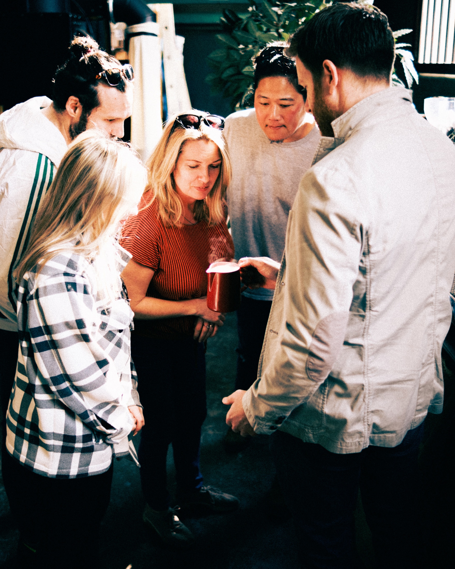 Four coffee enthusiasts looking into a jug of steamed milk that an Iron & Fire barista trainer is holding.